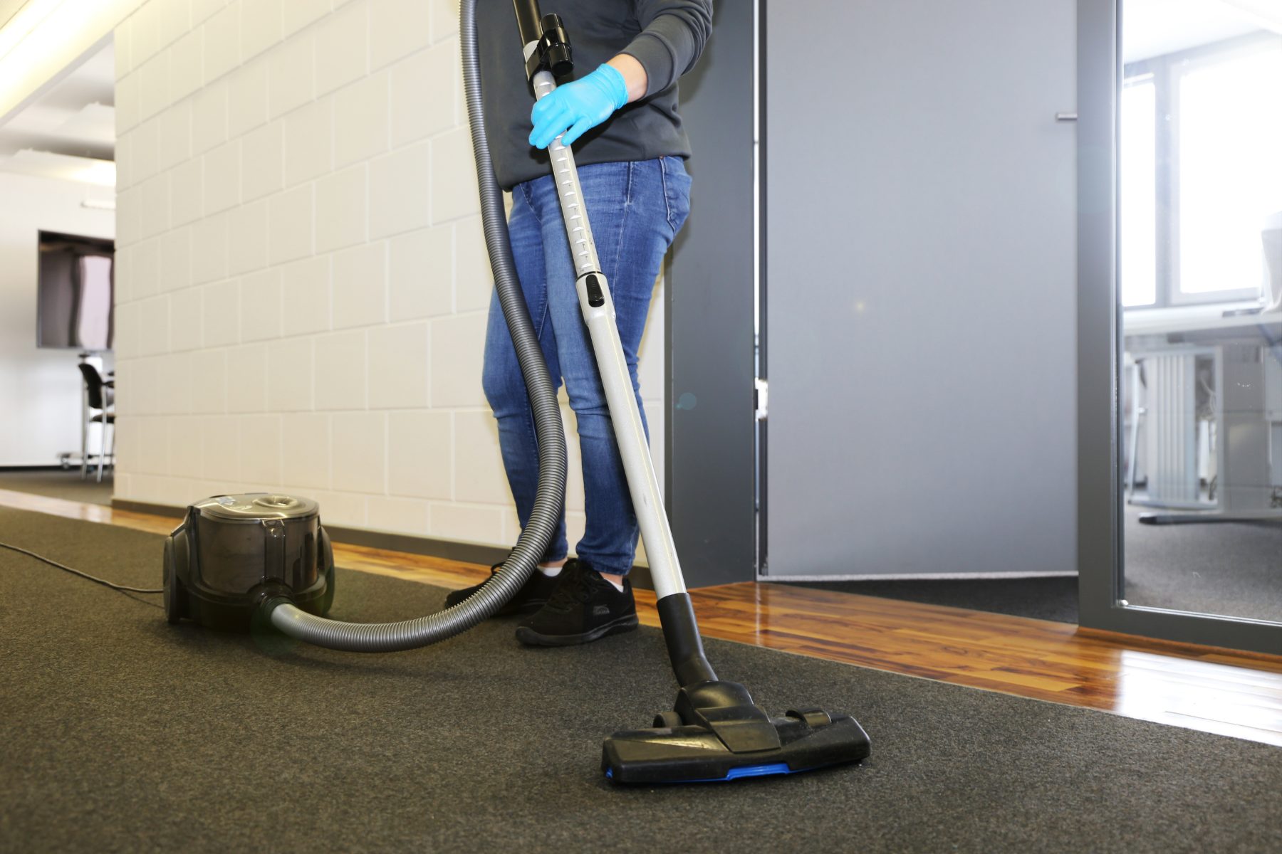 Cleaner vacuuming an office corridor carpet after hours